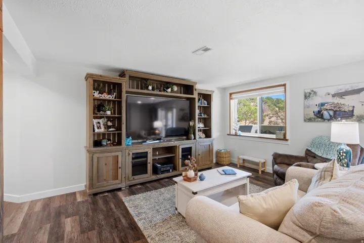 Living space featuring wood-finish flooring, a built-in media center with shelving, white painted walls, and a large window with white trim