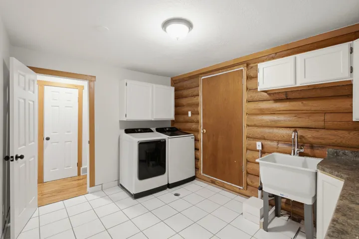 Laundry area with white tile flooring and log-style wall paneling