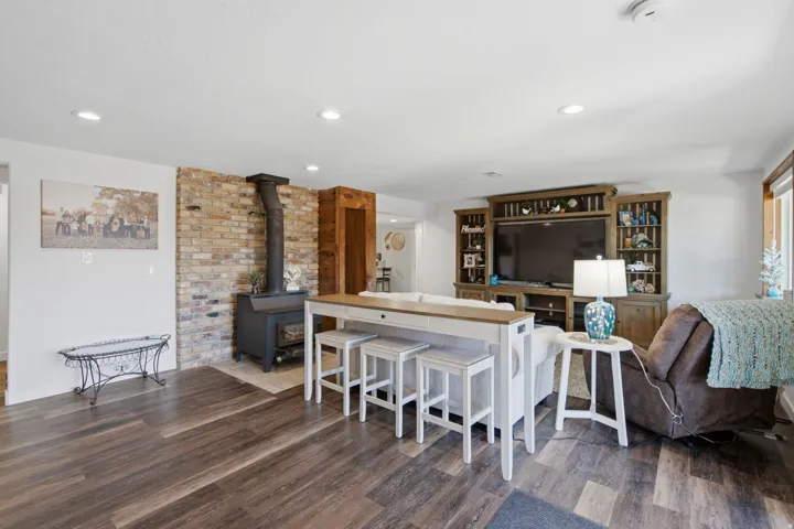 Spacious living area featuring wood-finish flooring, a brick accent wall, and recessed lighting