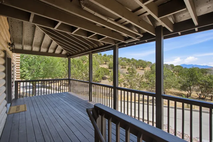 Spacious covered porch with wood-finish decking and dark wood railings