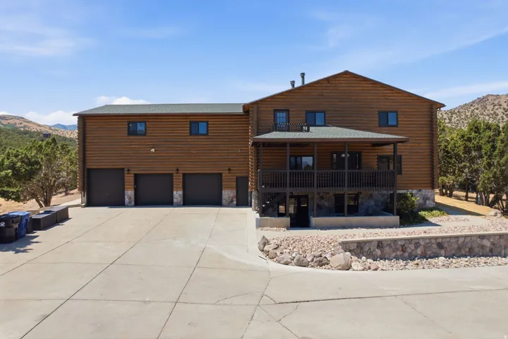 Wood-sided exterior featuring a covered porch, stone foundation, and a three-car garage