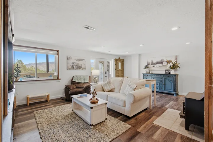 Bright living area with wood-finish flooring, recessed lighting, and a large picture window showcasing a mountain landscape