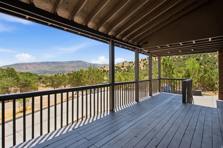 Spacious covered deck featuring wood-finish flooring, a wood railing, and exposed beam ceiling