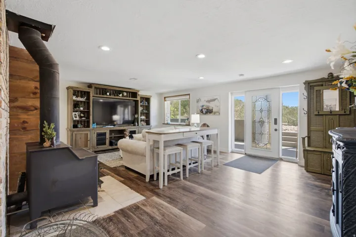 Open-concept living area with wood-finish flooring, recessed lighting, and a prominent wood-burning stove
