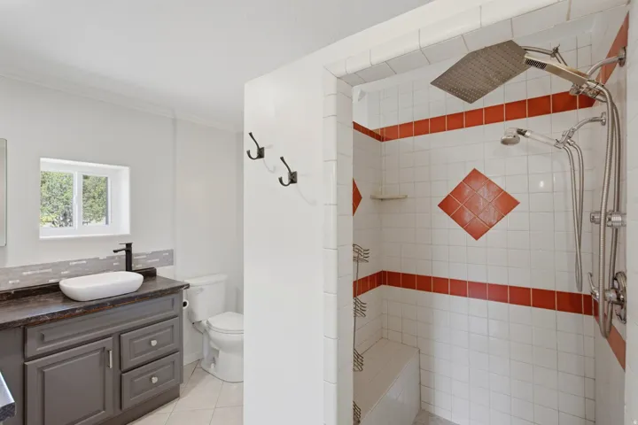 Walk-in shower with a rain shower head, handheld sprayer, and built-in bench