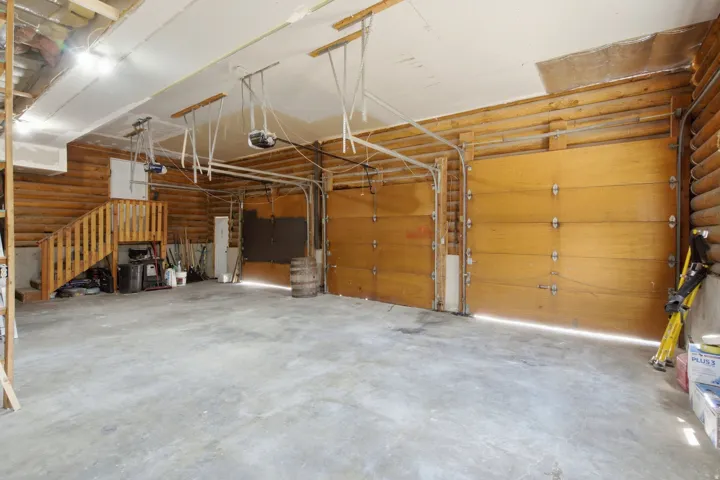 Spacious garage featuring a concrete floor, exposed wood beam construction, and two wooden garage doors