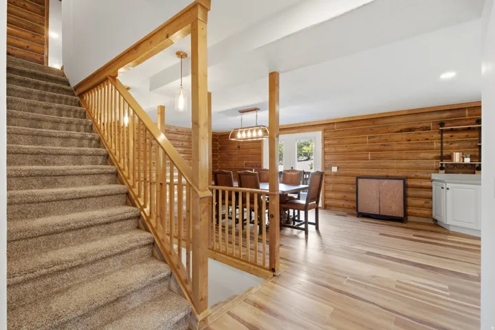 Carpeted staircase with wood-finish railing, wood-finish flooring, wood-paneled walls, built-in cabinetry, and recessed lighting