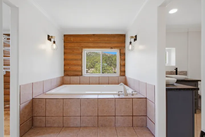 Soaking tub with a tiled surround and light wood paneling