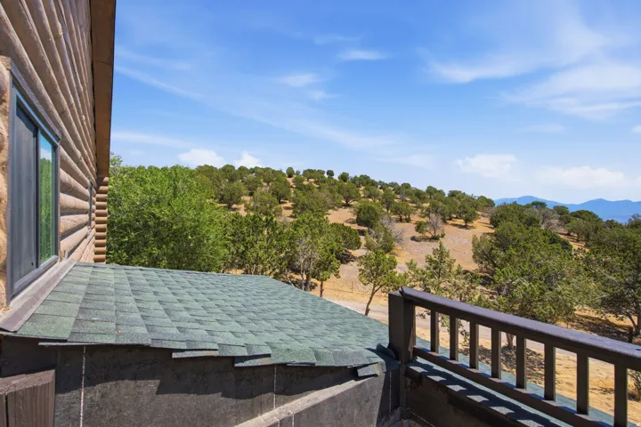 Wood-sided exterior featuring a window overlooking expansive natural terrain with scattered trees and distant mountains