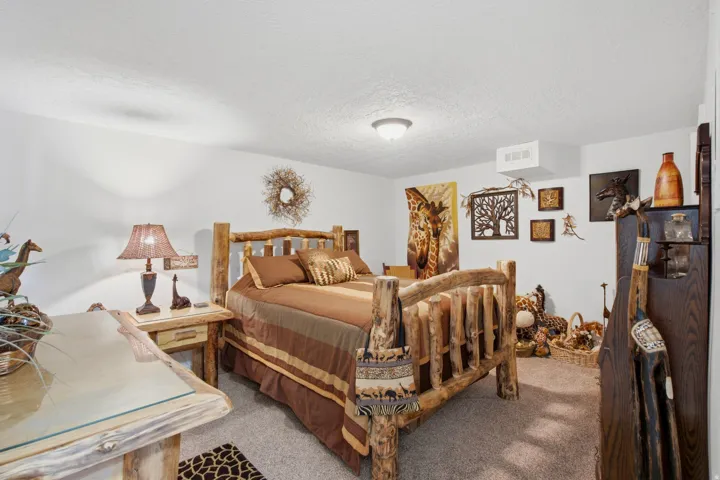 Carpeted bedroom featuring a rustic wood bed frame, matching nightstand, and a built-in wall shelf