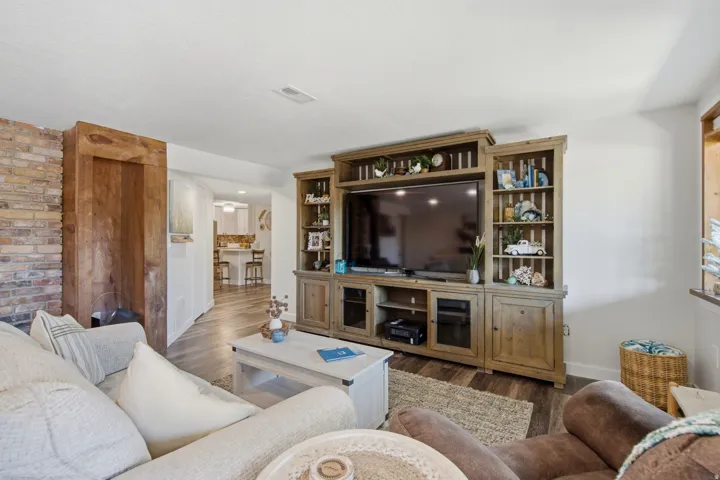 Living area featuring wood-finish flooring and a built-in entertainment center with shelving and cabinet storage