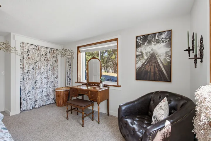 Carpeted interior space featuring a window with wood trim, white walls, and a recessed area with a curtain