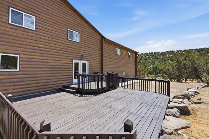 Expansive outdoor deck featuring dark wood railings and a direct entry point via French doors