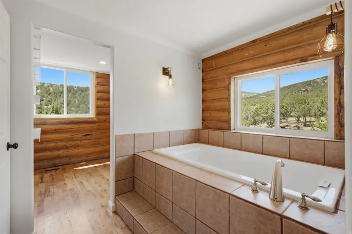 Soaking tub with tiled surround and integrated steps, featuring brushed nickel fixtures