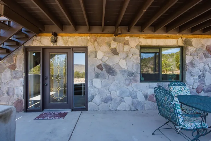 Exterior stone facade featuring a central entry door with decorative glass, two sidelight windows, and an overhead outdoor sconce