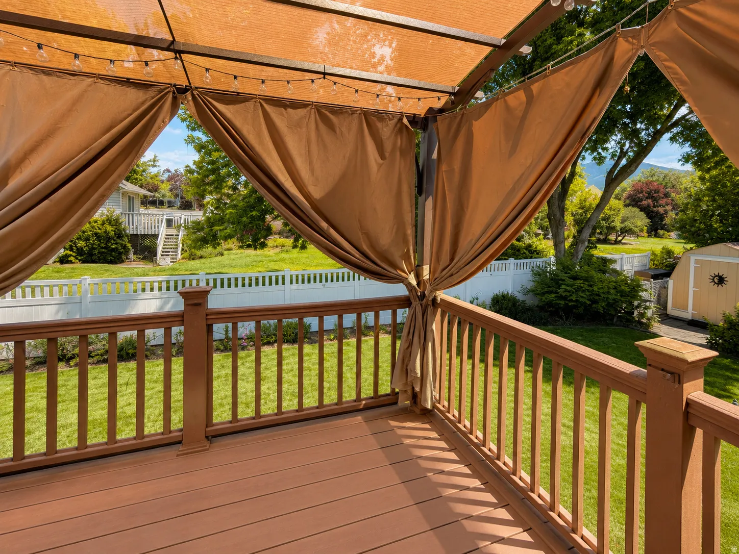 Expansive outdoor deck featuring composite decking, a brown railing system, and a pergola with retractable fabric panels