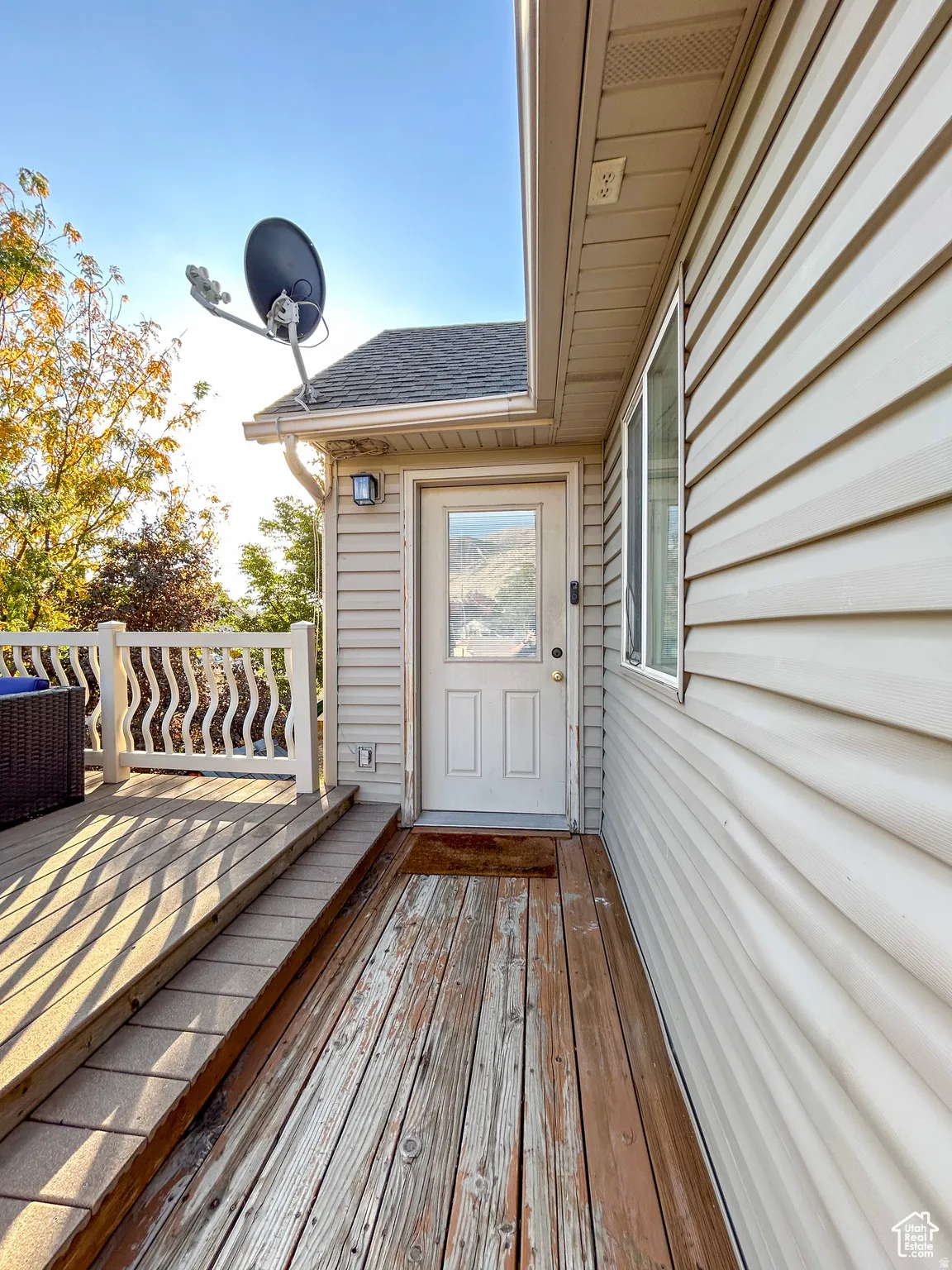 Side exterior entry featuring an outdoor light fixture, a glass-paneled door, and beige horizontal siding