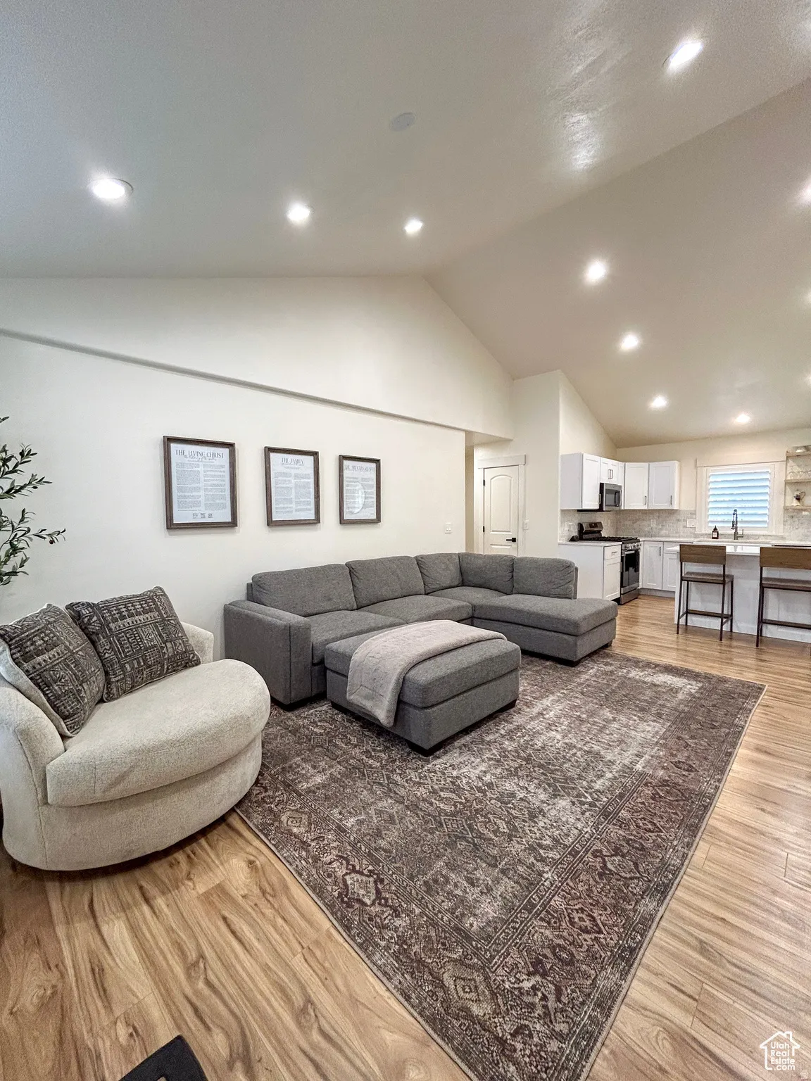 Spacious open-concept living area featuring vaulted ceilings, recessed lighting, and wood-finish flooring