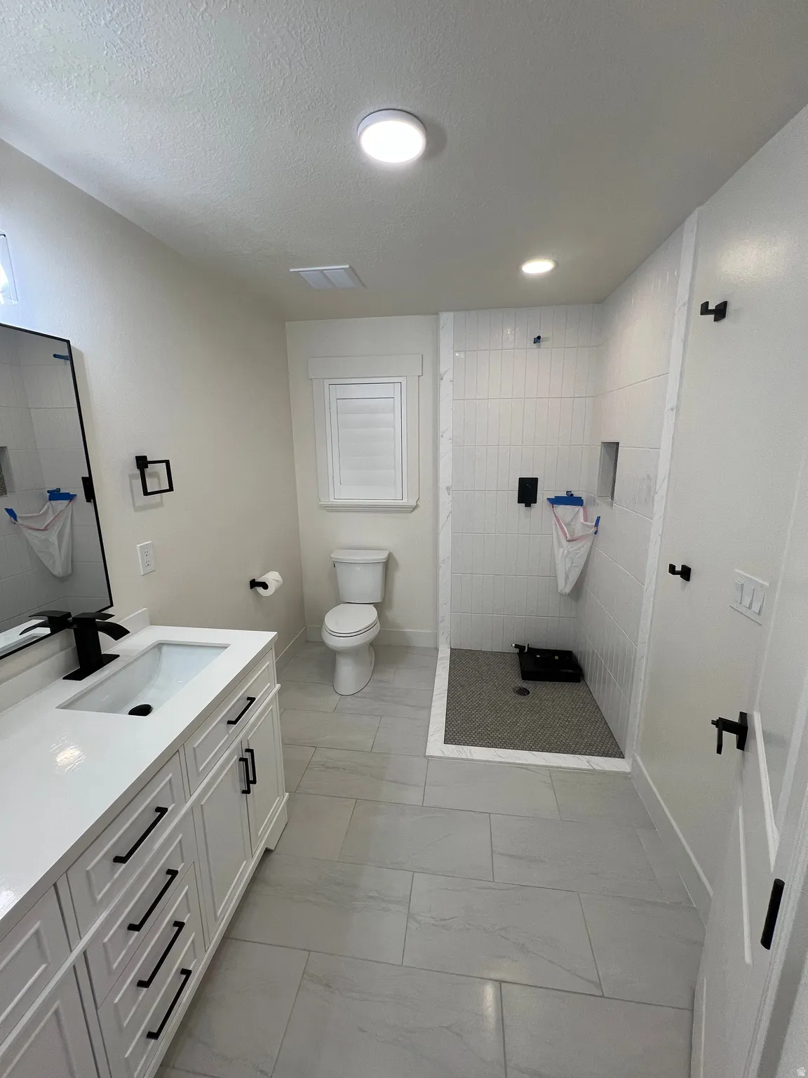 Modern bathroom featuring a white vanity with black hardware, an undermount sink, and a black-finish faucet