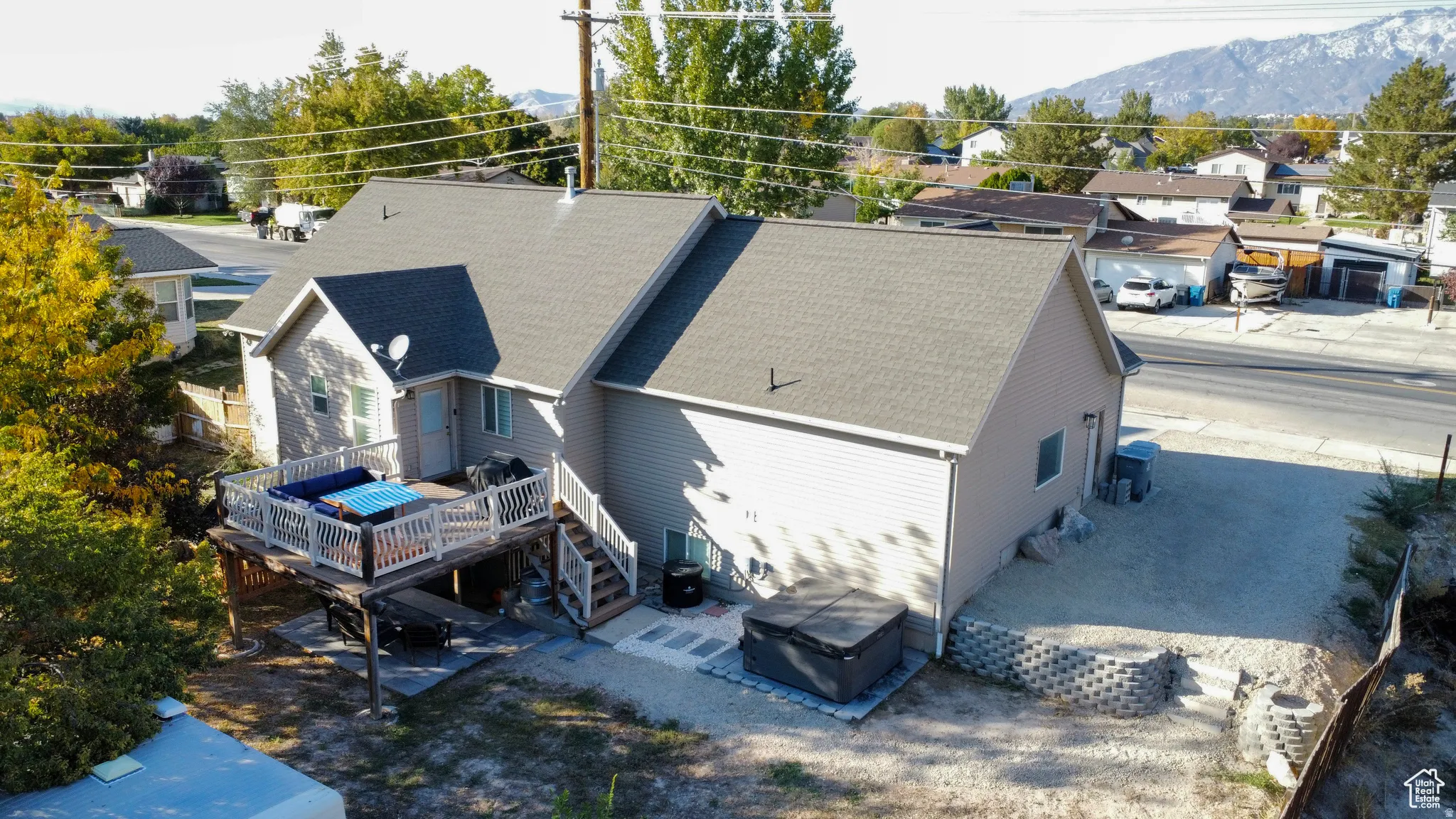 Rear exterior featuring a multi-level deck with white railings, stairs to ground level, and a gravel patio area