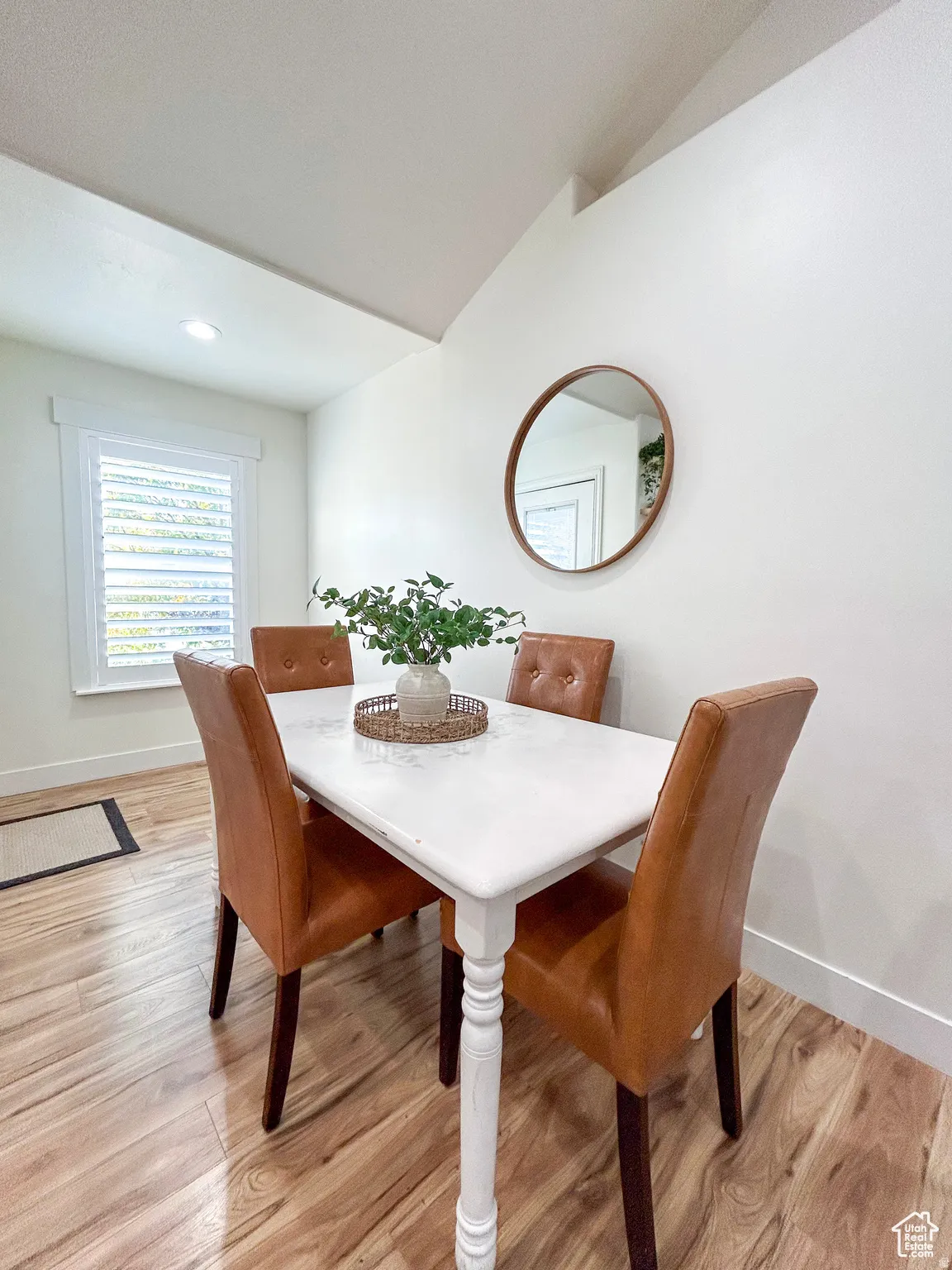 Dining area featuring wood-finish flooring, a white window with plantation shutters, a vaulted ceiling, and recessed lighting