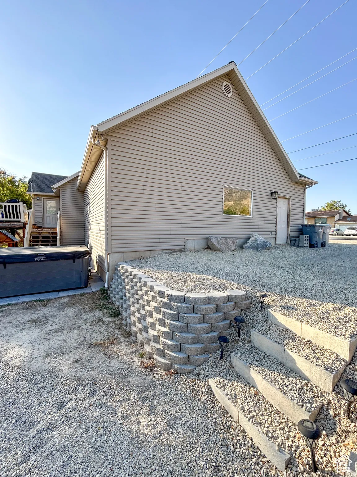 Exterior featuring gravel landscaping, a tiered stone retaining wall, and concrete stairs