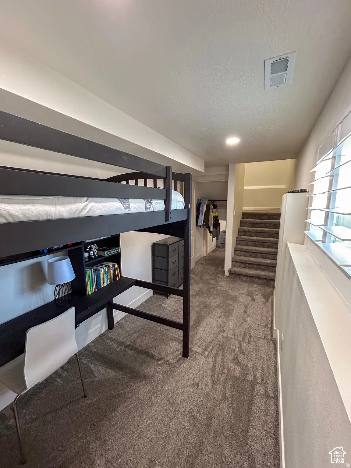 Built-in loft bed with integrated desk and shelving, recessed lighting, and soft carpet flooring