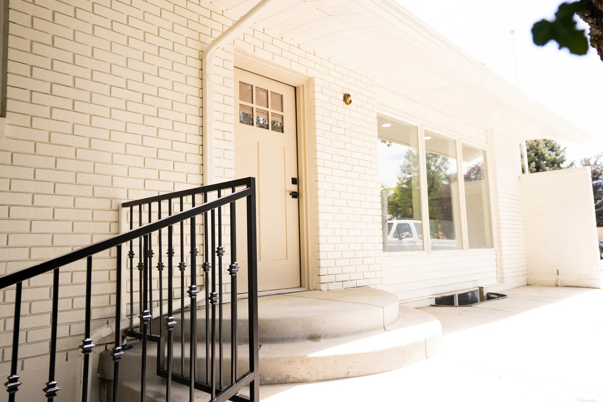White brick exterior with a beige front door featuring divided lites