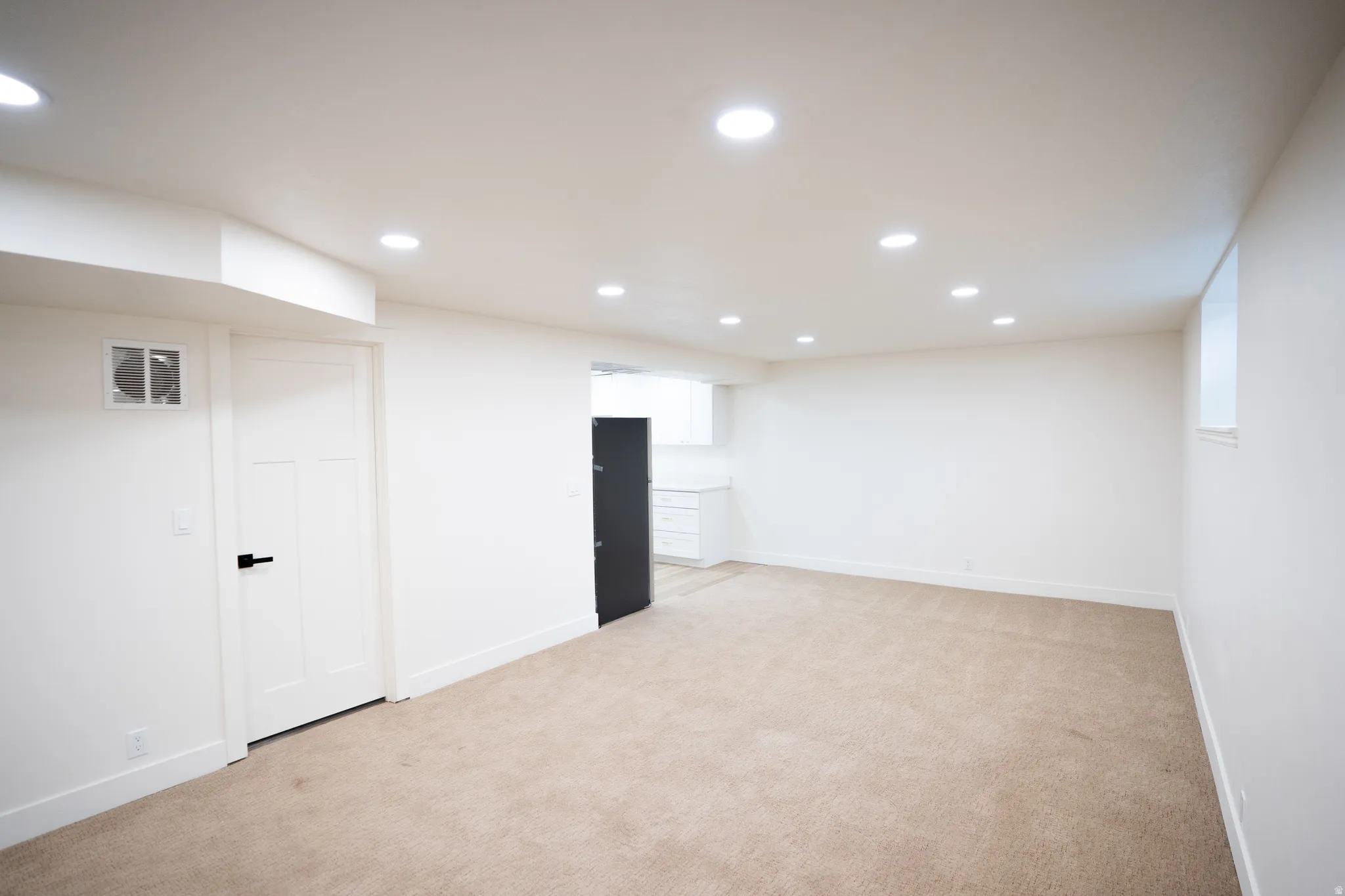 Spacious room with recessed lighting, light-toned carpeting, white walls, and a window