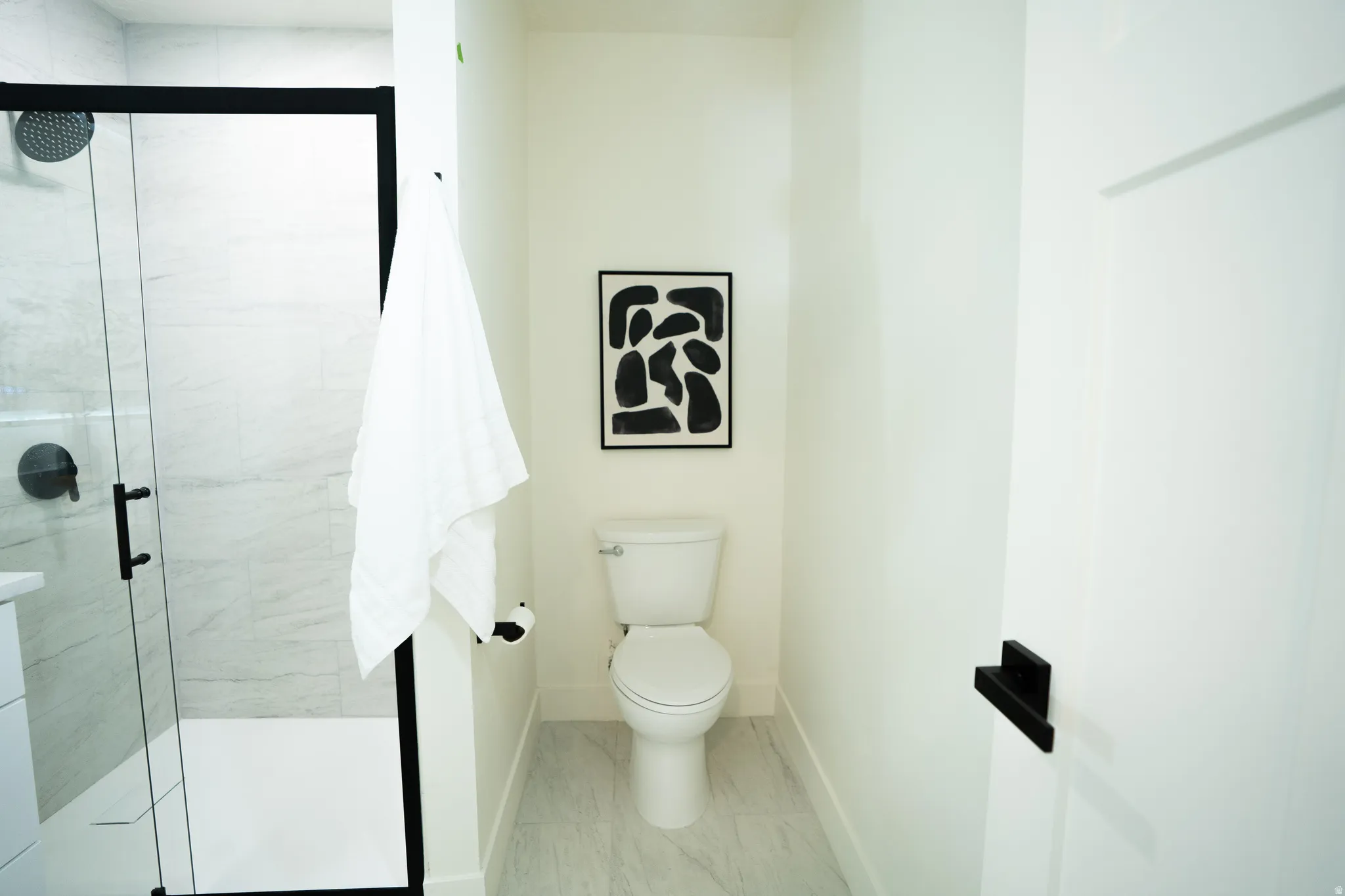 Modern bathroom featuring a glass-enclosed shower with black framing and hardware