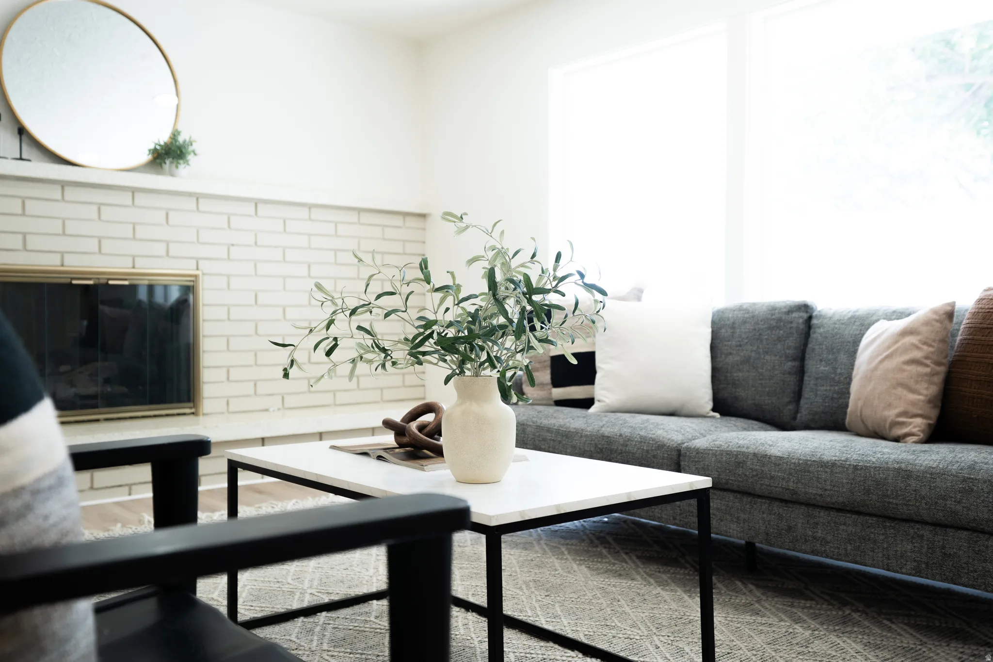 Living area featuring a white brick fireplace with a brass fire screen and a white mantel