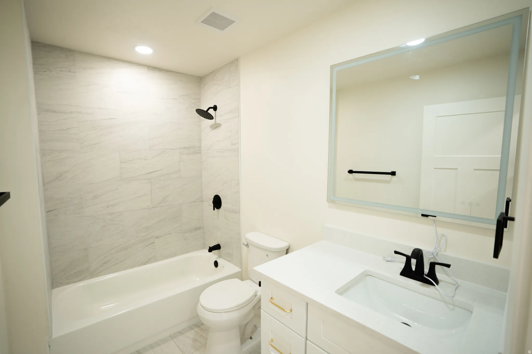 Bathroom featuring a white vanity with gold-tone hardware, a white countertop, and a recessed sink with a matte black faucet