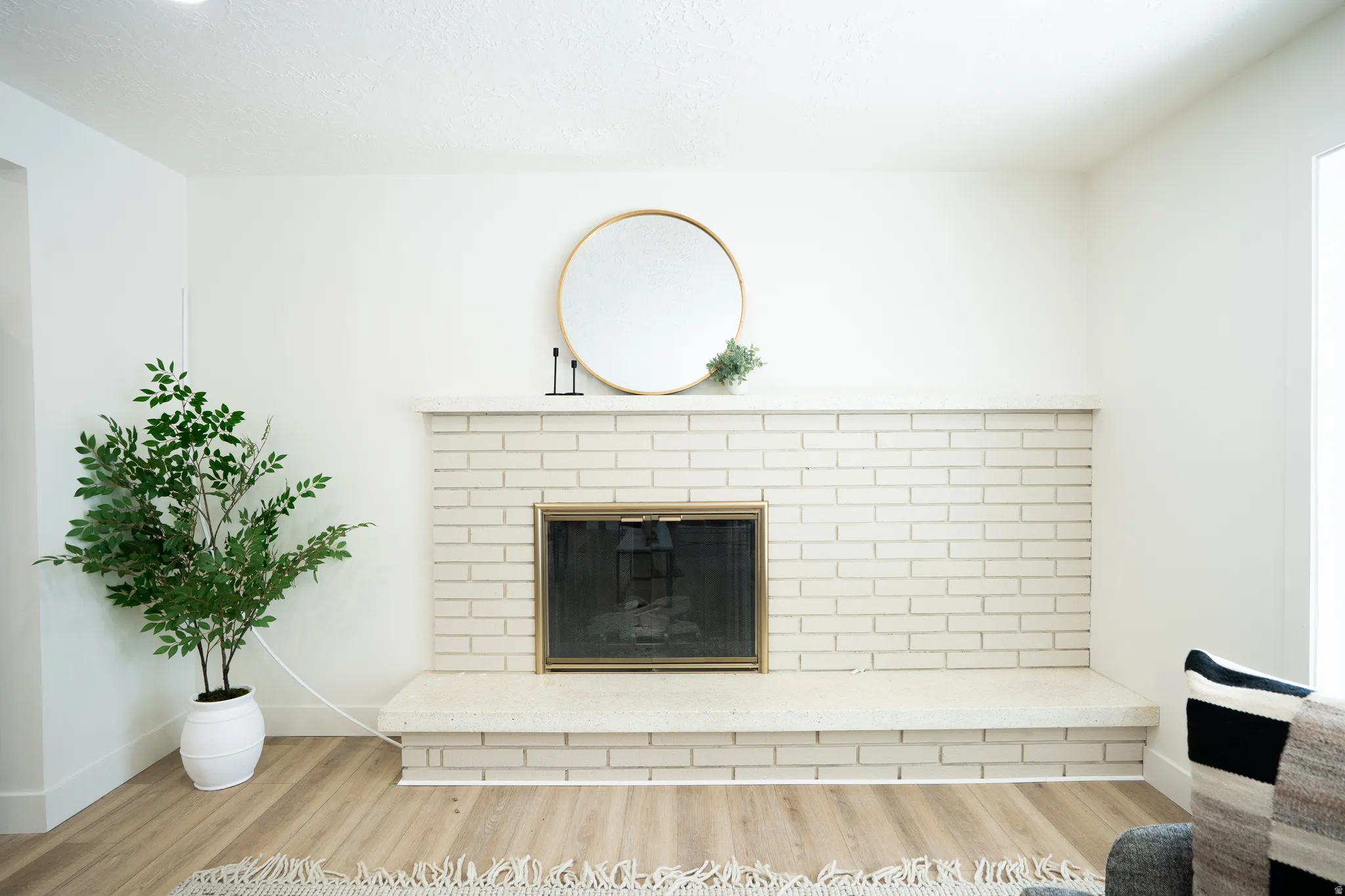 Fireplace with painted brick surround and hearth, featuring a brass-toned firebox