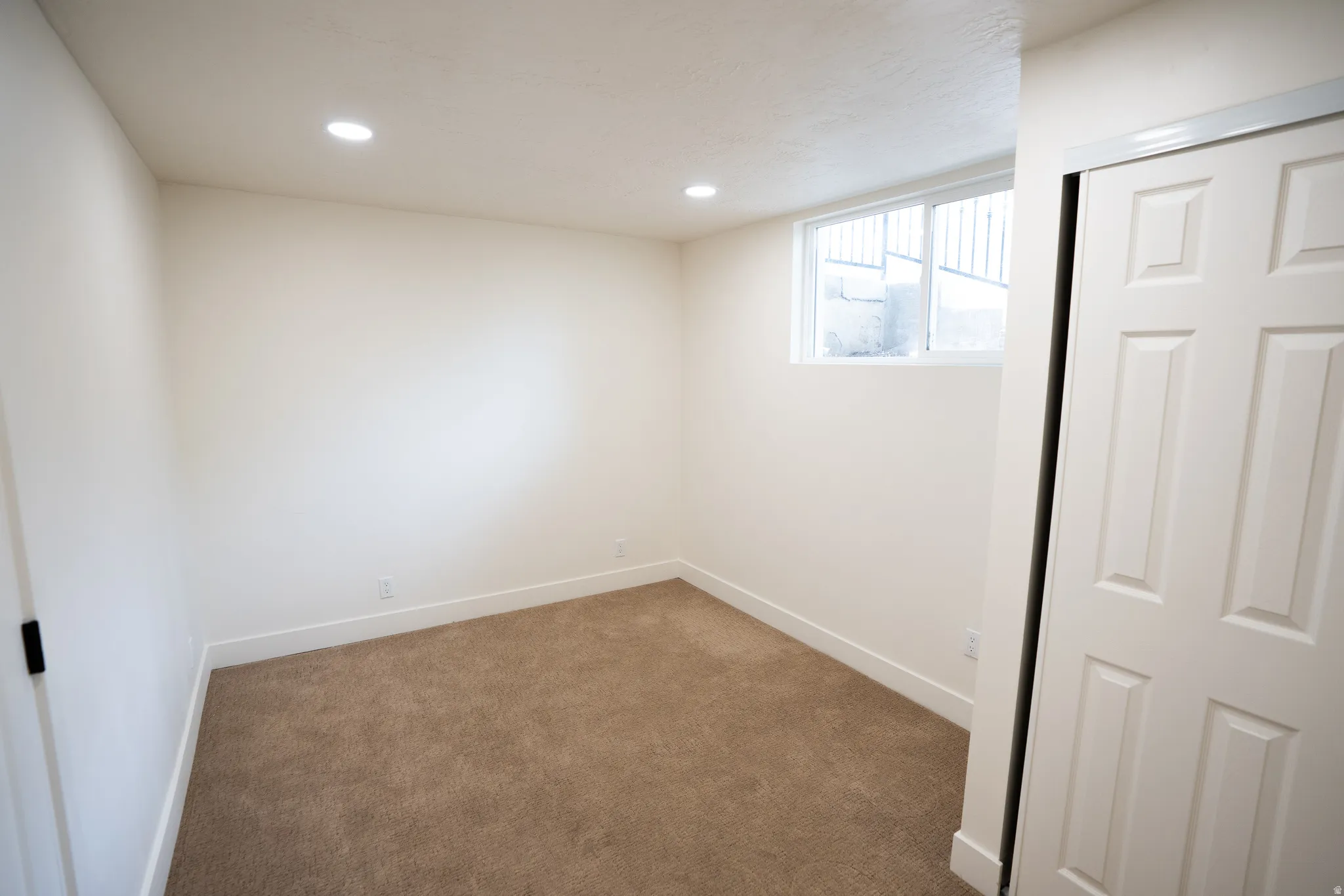 Carpeted room featuring recessed lighting, a window, baseboards, and a white paneled closet door