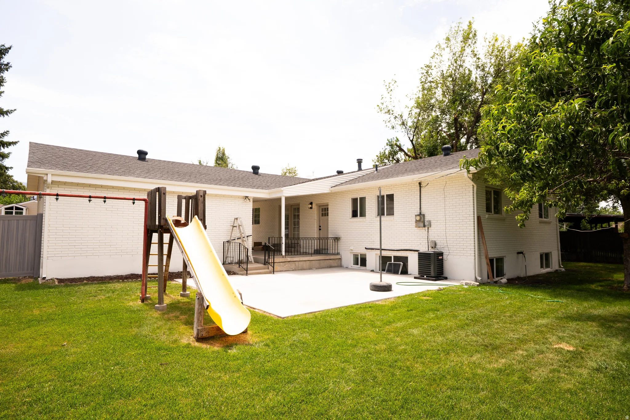 Expansive green lawn with a white brick exterior and a large concrete patio