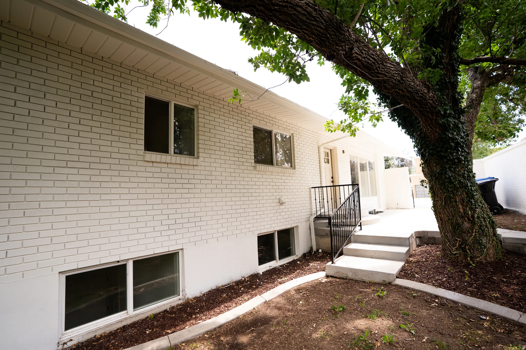 White brick exterior with a concrete patio featuring steps and black metal railings