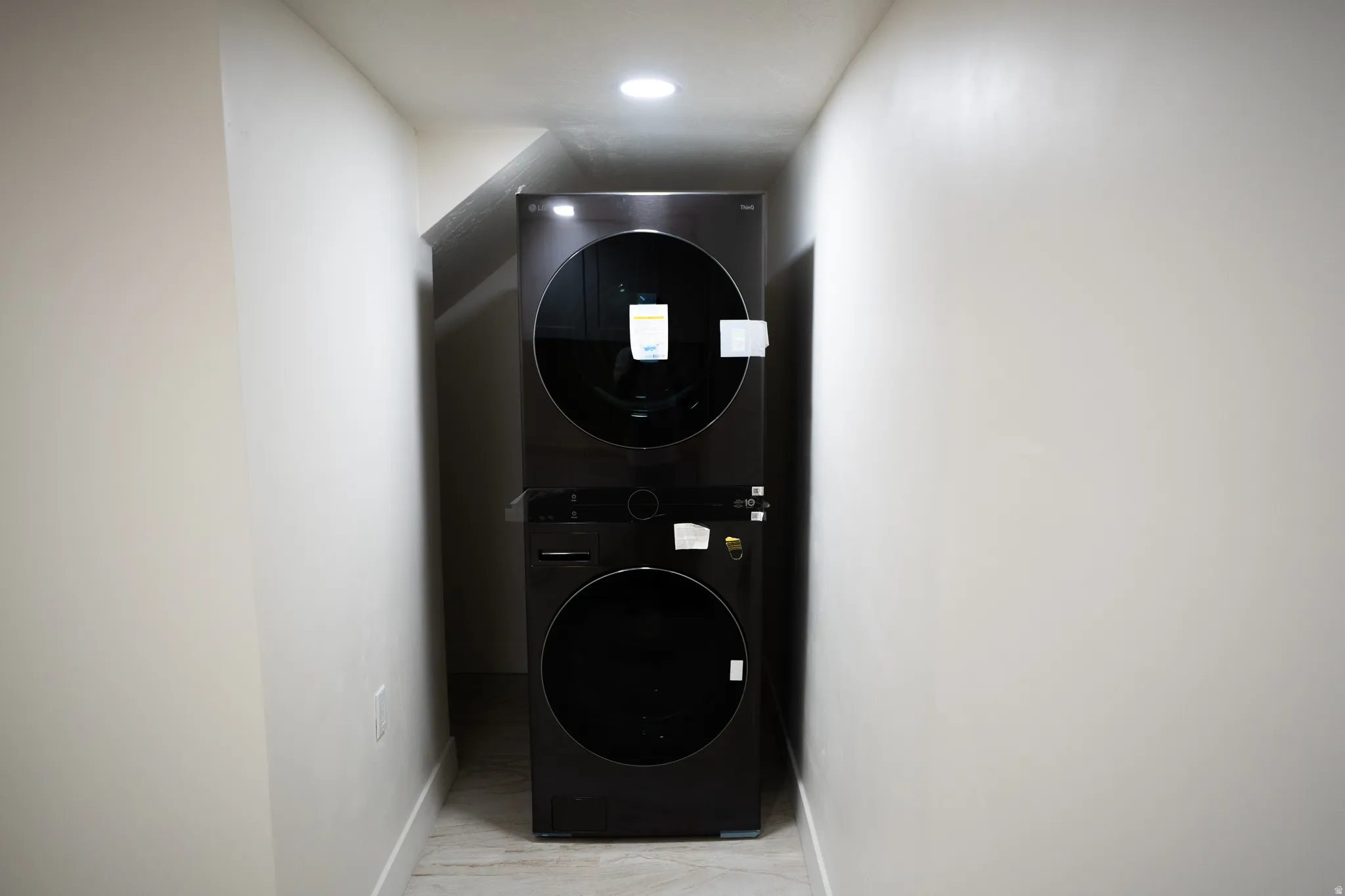 Laundry area featuring a new stacked washer and dryer unit