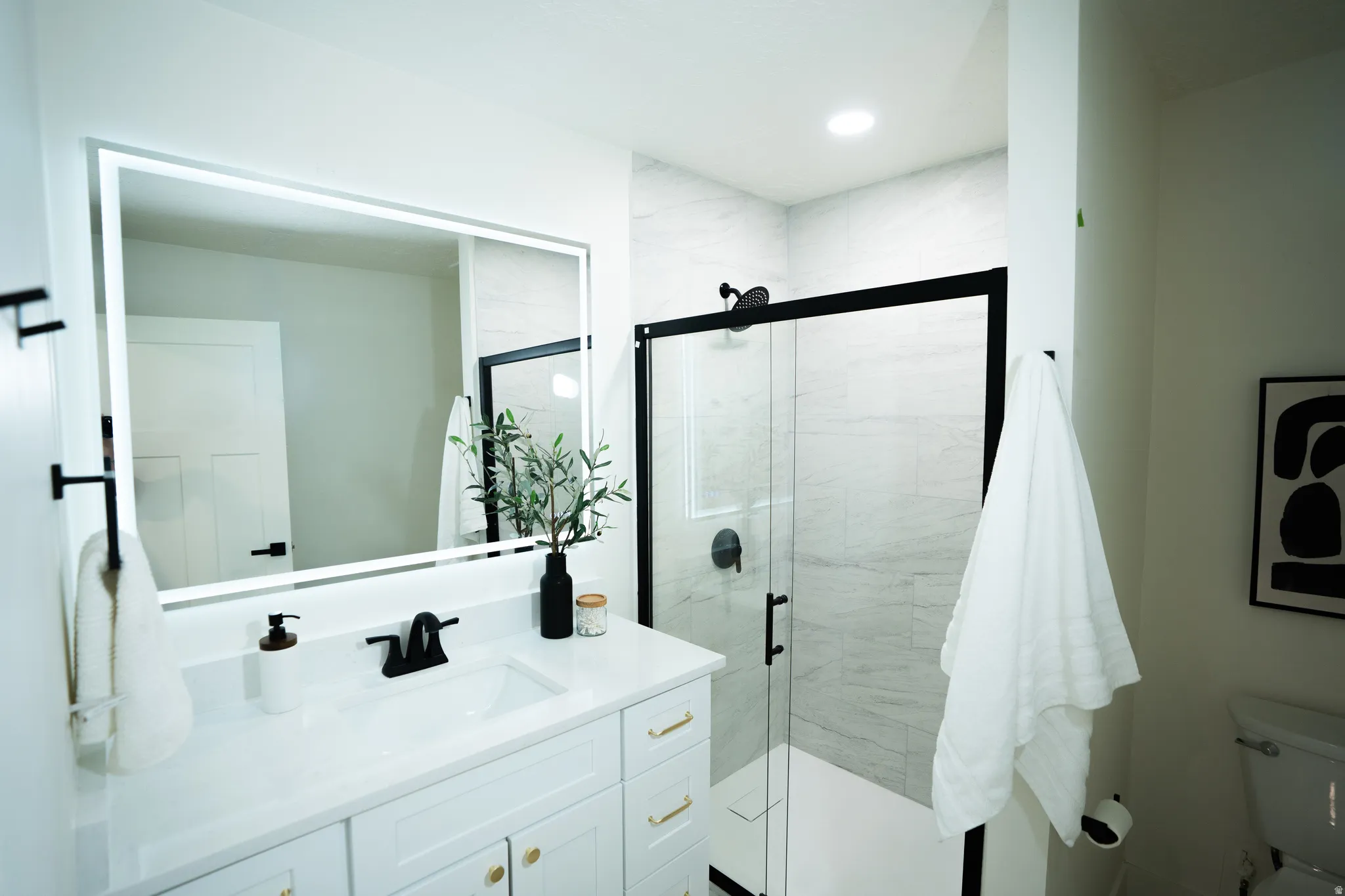Bathroom featuring a white vanity with gold-tone hardware, a white countertop with an integrated sink, and matte black plumbing fixtures