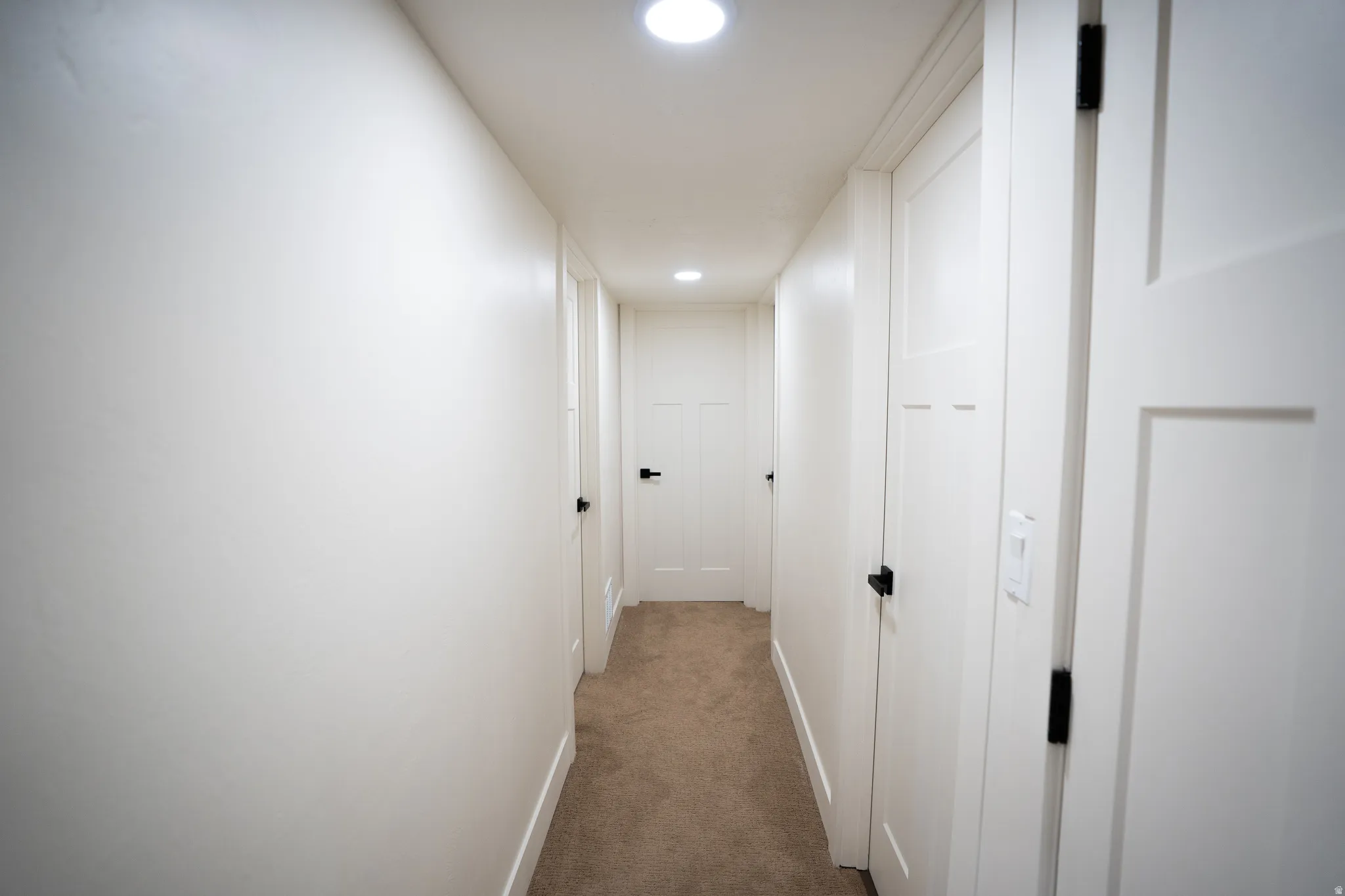 Hallway featuring recessed lighting, white doors with matte black hardware, and carpet flooring
