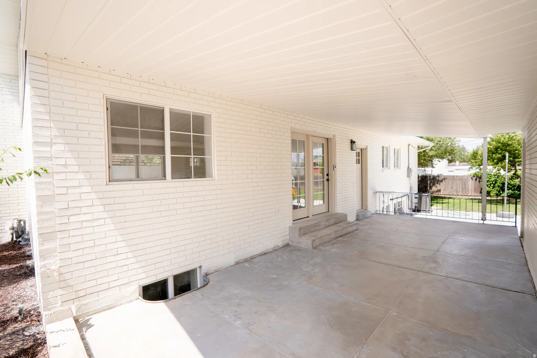 Covered patio featuring a concrete slab and white brick exterior