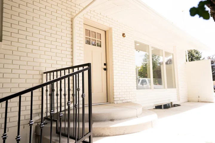 White brick exterior with a beige front door featuring divided lites
