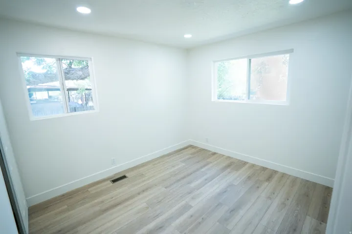 Room featuring wood-finish flooring, two windows, recessed lighting, and white baseboards