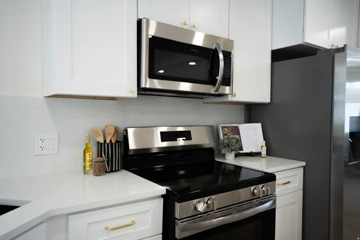 Kitchen featuring white cabinetry, light-toned countertops, and stainless steel appliances including a built-in microwave and range