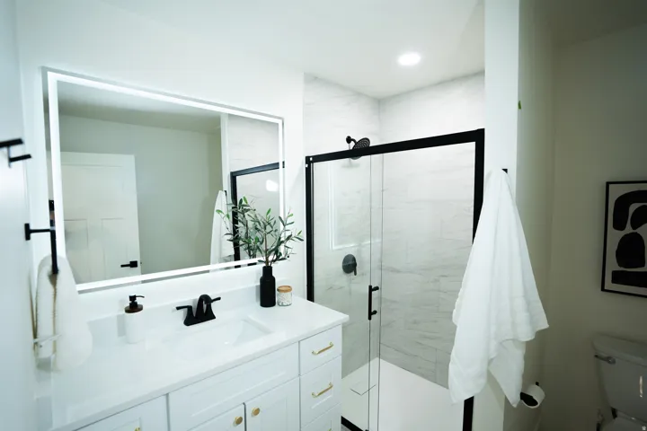 Bathroom featuring a white vanity with gold-tone hardware, a white countertop with an integrated sink, and matte black plumbing fixtures