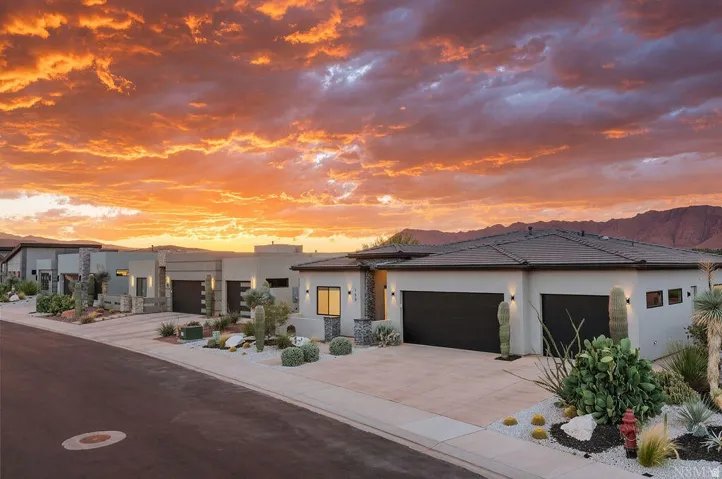 Modern stucco exterior with dark-toned garage doors, accentuating stone elements, and low-maintenance xeriscape landscaping