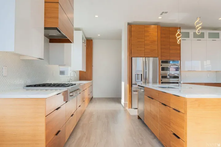 Contemporary kitchen featuring wood-finish cabinetry, white countertops, and stainless steel appliances