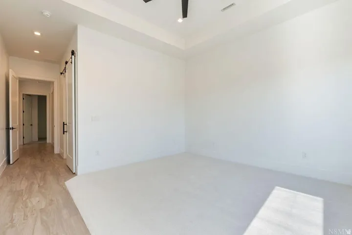 Spacious room with white carpeting, a tray ceiling, and recessed lighting