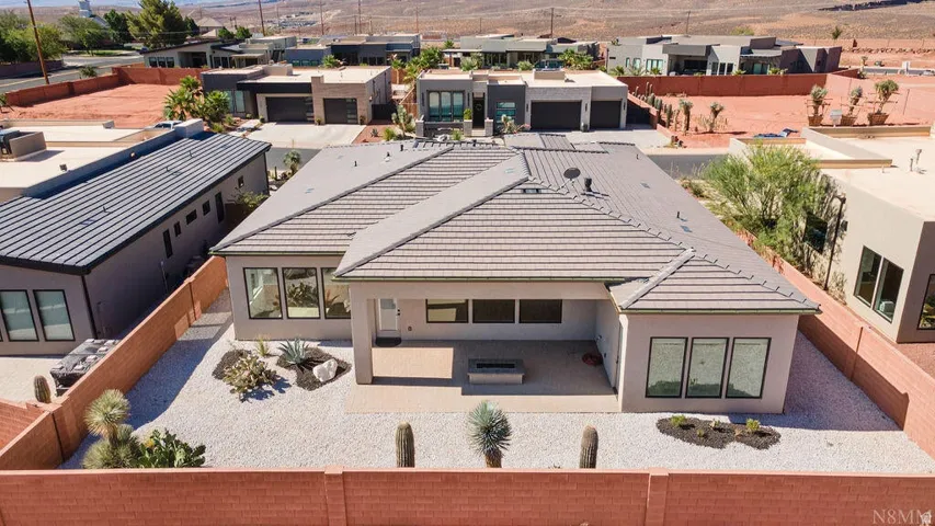 Rear exterior featuring a covered patio, desert-inspired landscaping, and a built-in fire pit