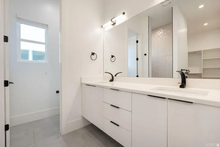 Double vanity featuring white cabinetry, integrated sinks, and matte black fixtures