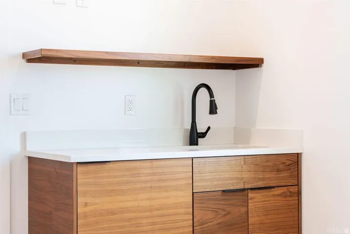 Wet bar featuring a matte black faucet, integrated sink, and white countertop